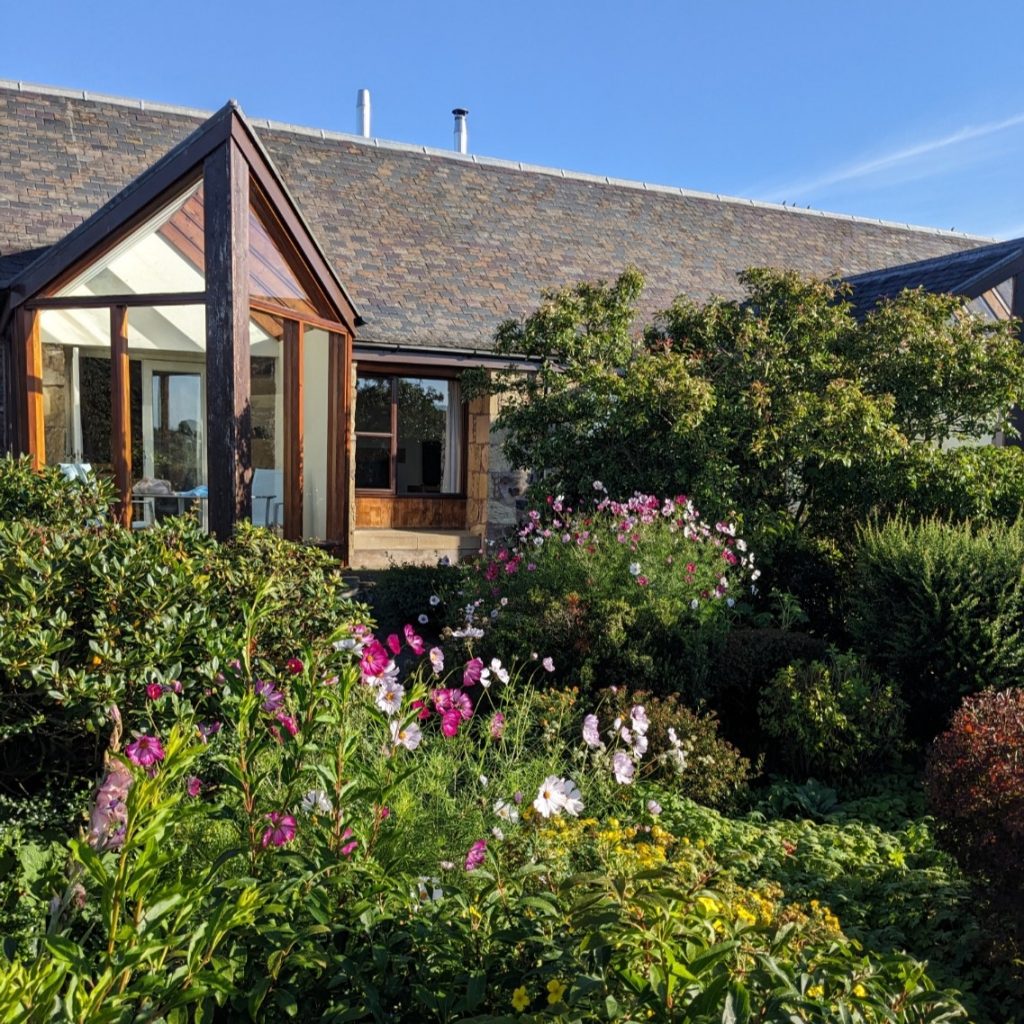Burnbrae Holidays Cottage garden with summer flowers and cottage conservatory. Holiday cottages in the Scottish Borders.