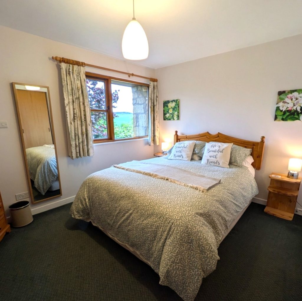 Thairn Holiday cottage has an extra long king sized bed in the bedroom. A large window looks out into the garden.