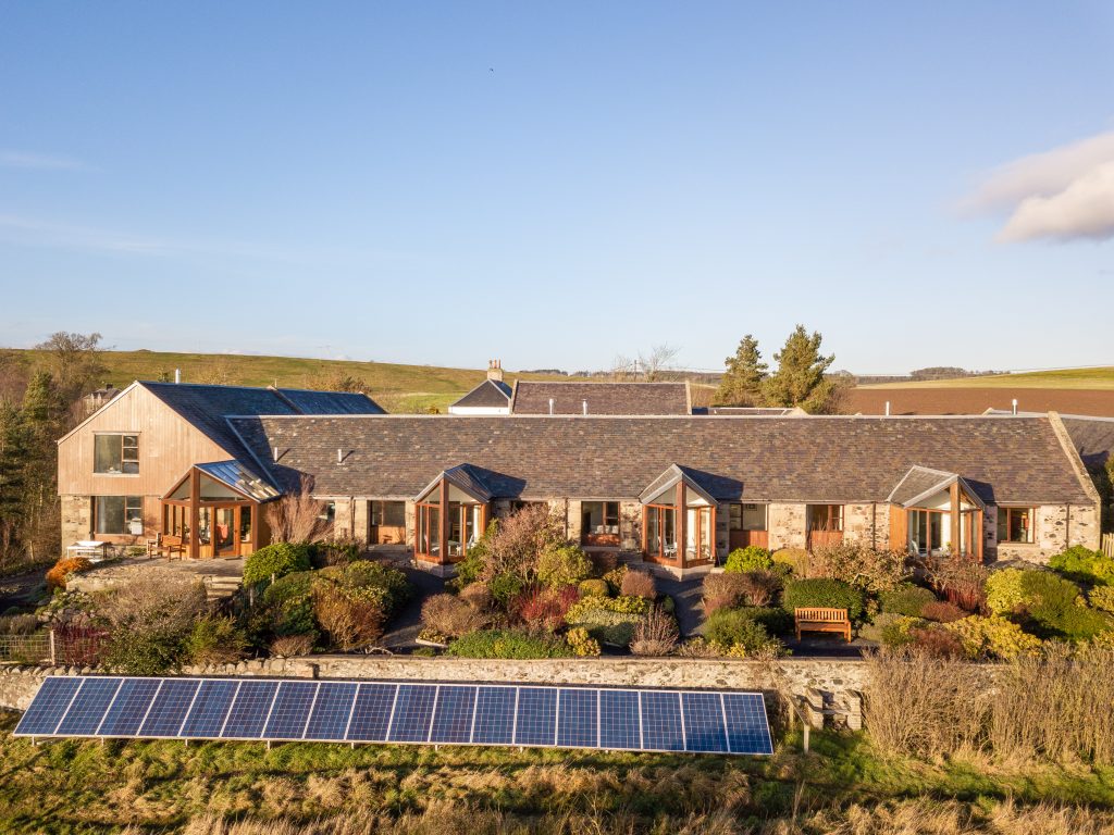 Burnbrae Holidays 3 holiday cottages from the air with the cottage garden. Solar panels in front of the garden wall.