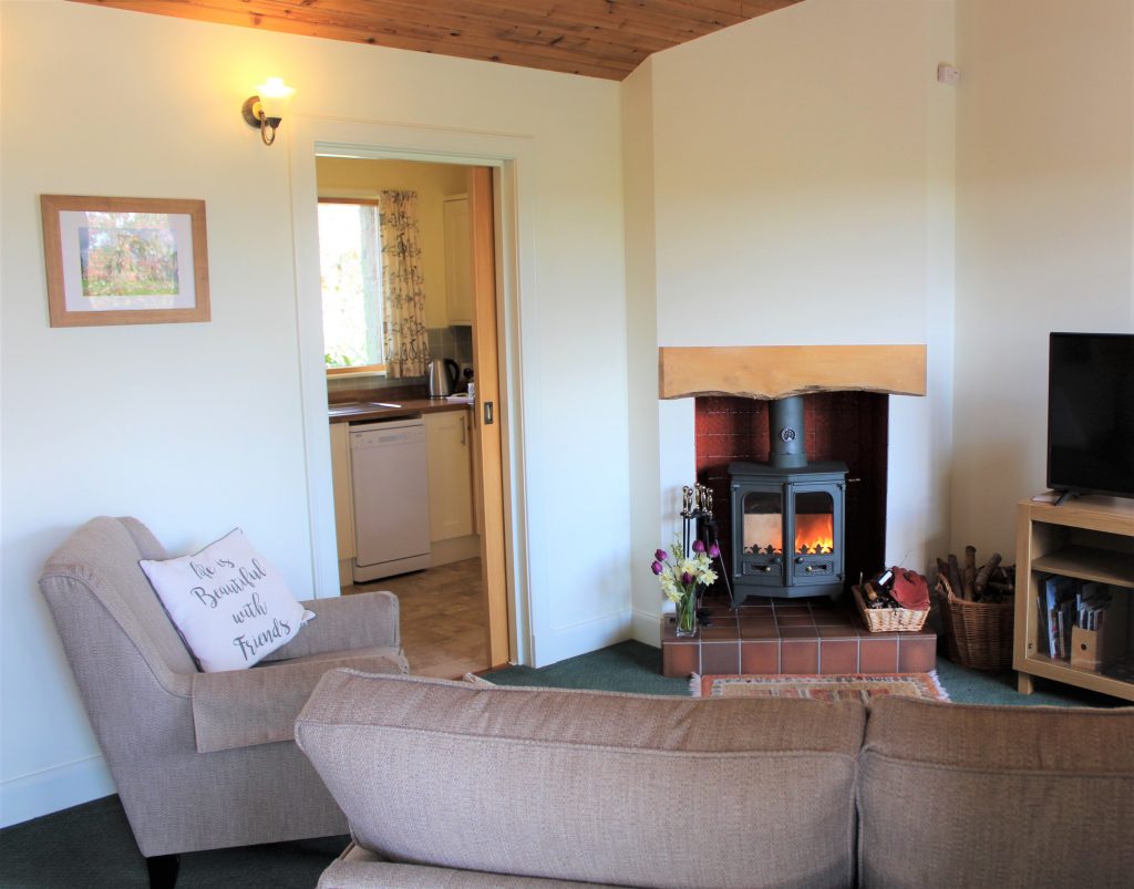 holiday cottage living room with wood burning stove and comfy settee and chair