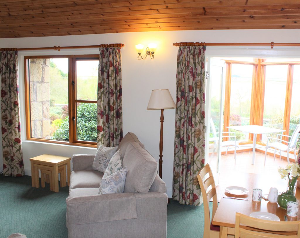 Holiday cottage living room with level access into garden room. Modern comfy settee and views into cottage garden.